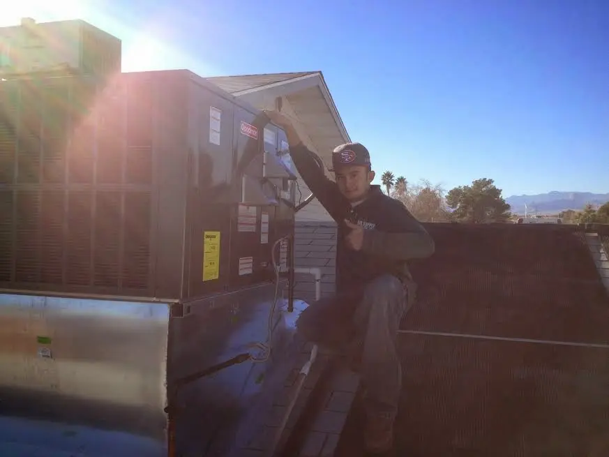 HVAC technician performing Air Duct Repair on a rooftop unit in Houlton